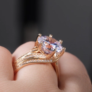 Detailed view of rose gold ring with a sparkling round zircon and pavé wave band on finger