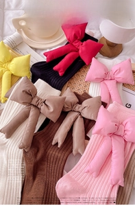 Detailed texture of knitted ribbed socks with oversized removable satin bow accents