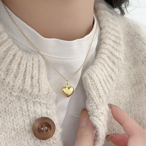 Close-up of a 925 sterling silver puffed heart pendant on a delicate gold chain