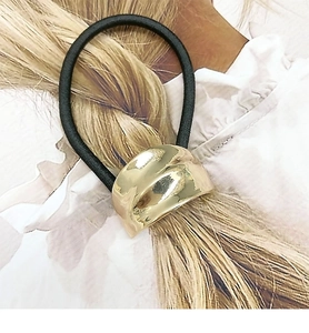 Close-up of a black elastic hair tie with a polished gold geometric metal buckle detail