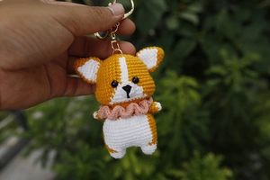 Detailed close-up of handmade crochet Corgi puppy keychain with pink wavy collar