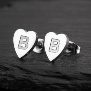 Macro shot of heart-shaped stainless steel earrings featuring an engraved letter B detail