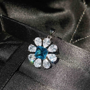 Close-up of blue topaz flower pendant with pear-cut white diamonds on black silk