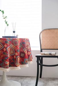 Detail of red jacquard round tablecloth with ethnic geometric patterns and fringe tassels
