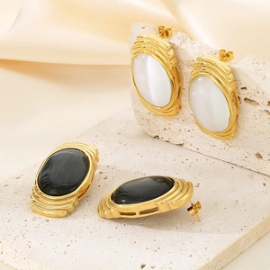 Detailed view of vintage gold-plated earrings with oval cat-eye stone on stone background