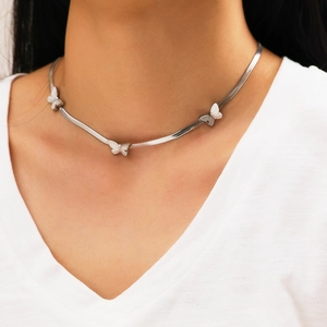 Detail showing a silver butterfly pendant snake chain necklace on a white shirt