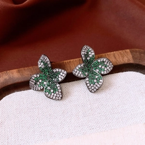 Detail of vintage flower earrings with green and white zircons on black metal base