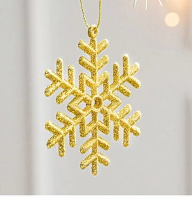 Close-up of golden glitter snowflake ornament hanging as a Christmas tree decoration