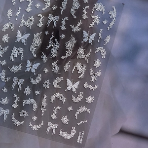 Detail of white embossed flower and butterfly nail stickers with sparkling crystal accents