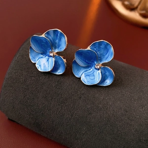 Vintage blue flower earrings with gold edges and crystal center on a luxury display