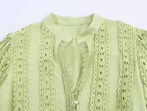 Detail of light green blouse featuring lace patchwork and a decorative pearl button