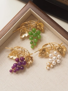 Three vintage grape brooches in white, green, and purple pearls on a wooden display tray