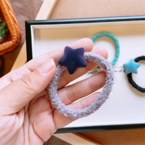 Dettaglio di un elastico in peluche grigio con stella blu in un ambiente accogliente