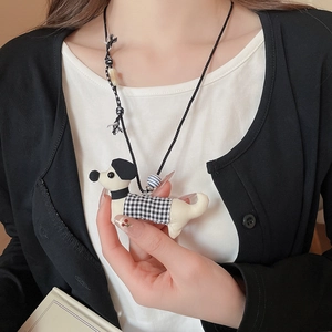 Detail view of cartoon dog pendant with plaid sweater and ceramic beads on a long necklace