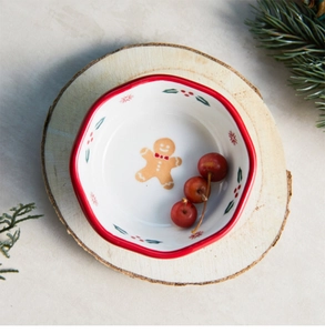 Close-up of a festive gingerbread man ceramic bowl on a wooden slice with red berries