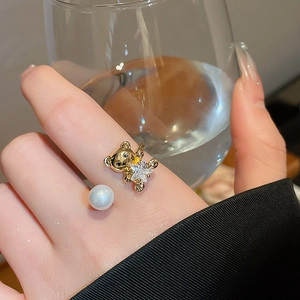 Detailed macro view of open ring featuring a golden bear, pearl, and zircon star