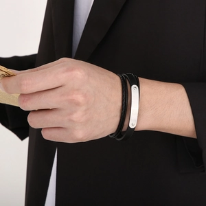 Primo piano di un bracciale multistrato in pelle nera da uomo con placca in metallo