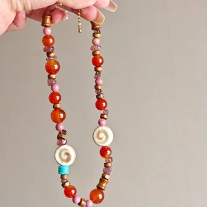 Bohemian beaded necklace with agate, wood beads and spiral shell accents held by hand