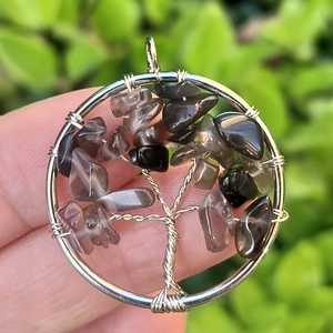 Close-up of handmade tree of life pendant with silver wire and natural grey stones