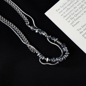 Close-up of silver double-layer necklace with black agate beads and cuban chain texture