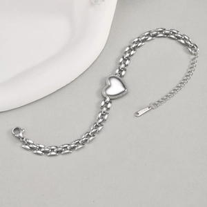 Close-up of silver stainless steel heart link bracelet with polished milgrain details