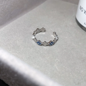 Detail eines silbernen offenen Rings mit blau-weißen Zirkonia-Kleeblatt-Motiven.