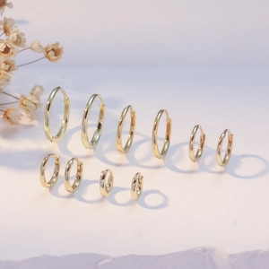 Detailed comparison of various sizes of polished gold hoop earrings with floral accents