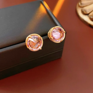 Macro view of 18k gold-plated stud earrings with pink-purple zircon on black leather box