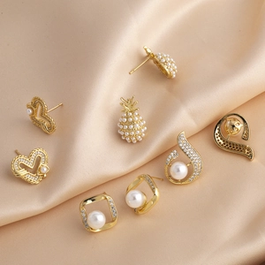 Elegant gold earrings collection with pearls and pineapple heart motifs on silk fabric