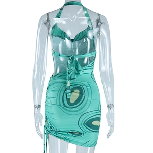 Back view of backless halter dress featuring green circular print and ruched detail