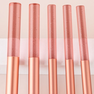 Detailed view of five mini makeup brushes with glitter crystal handles and rose gold ferrules