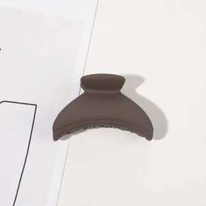 Detail of dark brown matte hair claw clip with anti-slip teeth and crescent shape design