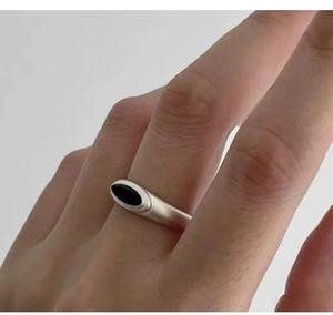 Detailed view of silver matte ring featuring a black oval onyx stone worn on finger