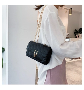Detail of classic black quilted shoulder bag with gold Y-lock and chain strap on model