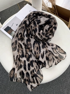 Close-up of leopard print scarf fabric showing semi-transparent texture and edge stitching