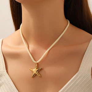 Collier pendentif étoile de mer doré avec chaîne en corde crème porté par un modèle