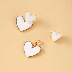 Macro view of gold heart jewelry set featuring white enamel earrings and matching pendant