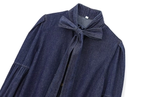Detail of dark blue denim shirt featuring a bow tie neckline and lantern sleeves texture