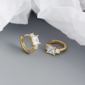 Macro shot of gold square zircon hoop earrings with a polished finish and three-stone design