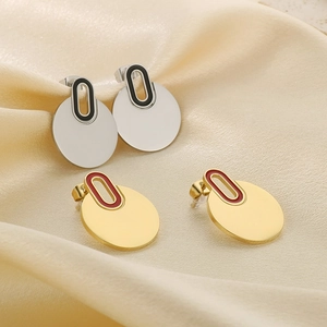 Macro view of gold and silver circular stud earrings on soft silk fabric background