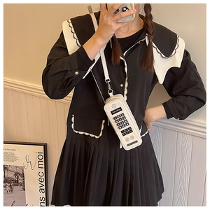 Close-up of white retro vintage phone shaped crossbody bag with keypad detail and strap