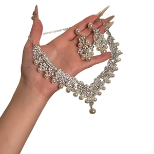 Elegant silver necklace and earrings set with white pearls and sparkling rhinestones