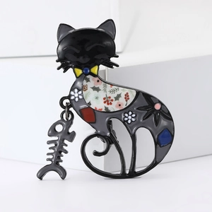 Detail of a black enamel cat brooch with floral patterns and a dangling fishbone charm