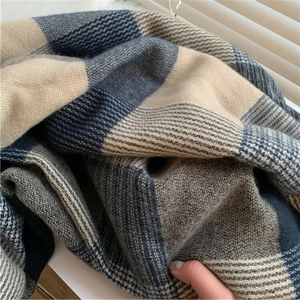 Classic blue and beige plaid scarf in soft cashmere-like knit fabric on a windowsill