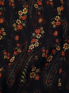 Macro shot of wrinkled black chiffon fabric with vintage red and yellow floral print
