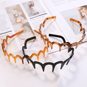 Three wavy tortoiseshell and black hairbands displayed on a white plate with a magazine