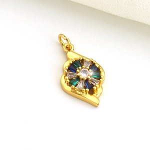 Close-up of golden paisley pendant with inlaid blue and green zircon gemstones