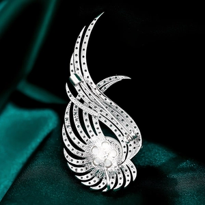 Gros plan d'une broche en forme d'ailes en argent avec zircons et une perle au centre
