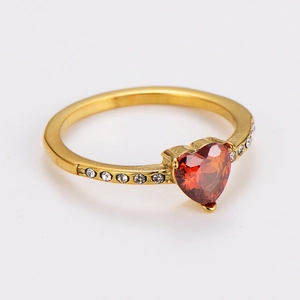 Close-up of gold heart ring with red gemstone and white diamonds on the band