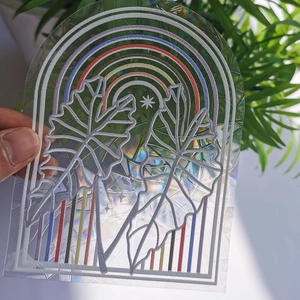 Rainbow prism suncatcher film with monstera leaf pattern on window glass